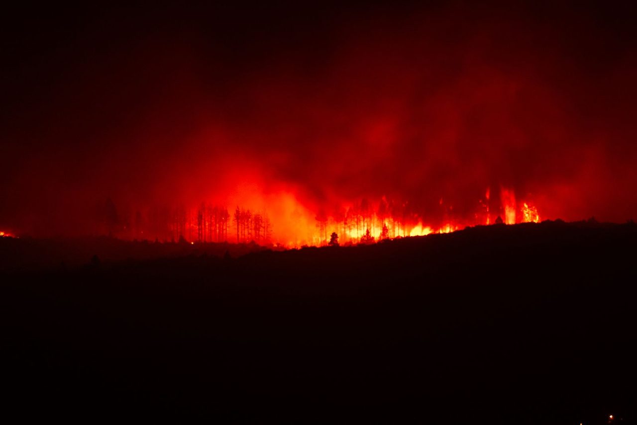 A dramatic evening sky over the fire zone as crews work to protect villages.